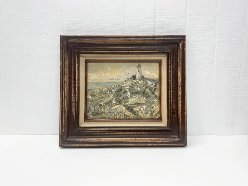 Framed coastal oil painting featuring a lighthouse